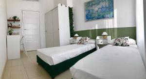 2 camas en una habitación con paredes verdes y blancas en Marco Polo GreenRoom en Milán