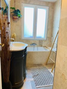 uma casa de banho com uma banheira, um lavatório e uma janela em Almanarre em Hyères
