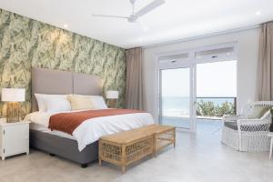 a bedroom with a bed with a view of the ocean at NKWAZI COTTAGE, 77 Nkwazi Drive, Zinkwazi beach in Zinkwazi Beach