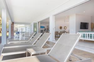 a row of white chairs in a living room at NKWAZI COTTAGE, 77 Nkwazi Drive, Zinkwazi beach in Zinkwazi Beach