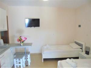 a room with a bed and a table and a tv on the wall at Zace Studios in Ksamil