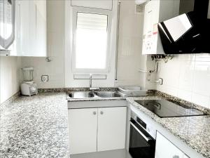 a white kitchen with a sink and a window at Open Sky, Apartamento con solárium privado y barbacoa in El Vendrell