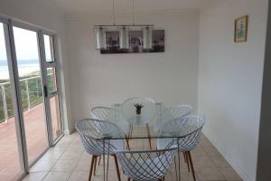 KingsboroughにあるLa Mer Stunning Beachfront Apartmentのダイニングルーム(ガラスのテーブル、椅子付)