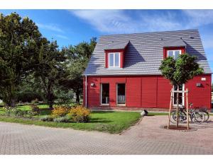 una casa roja con un árbol delante en Ferienwohnung Rote Kate, en Born