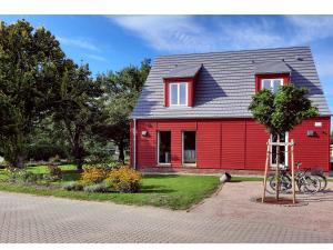 a red house with a tree in front of it at Ferienwohnung Rote Kate in Born