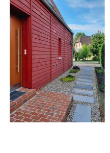 een rood gebouw met een bakstenen loopbrug naast een huis bij Ferienwohnung Rote Kate in Born