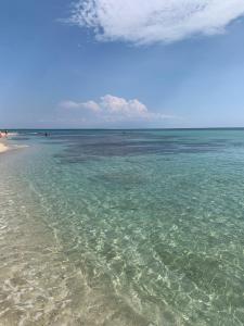 una playa con agua clara y gente a lo lejos en Samanà Bed and Breakfast, en Punta Prosciutto
