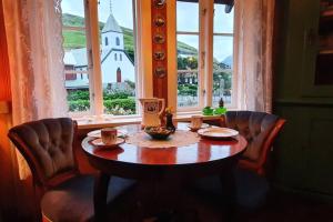 a table and chairs in a room with a window at Charming and Authentic Heritage Retreat in Kvívík - right next to the river in Kvívík
