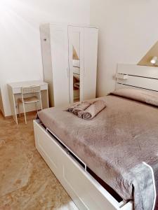 biała sypialnia z łóżkiem i biurkiem w obiekcie "Nonna Maria" w mieście Venegono Superiore