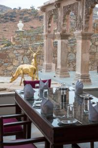 una mesa de comedor con una estatua de ciervo en el fondo en Fateh Safari Resort by Fateh Collection, en Kumbhalgarh