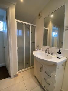 a white bathroom with a sink and a shower at Shack out the Back in Kyneton