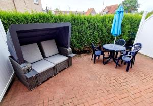 a patio with a couch and a table and an umbrella at Ferienwohnungen Saida Wohnung 5 in Norden