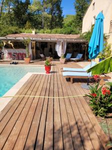 a wooden deck next to a swimming pool with a blue umbrella at 1262 Chemin des Pignatelles in La Motte +9 photos