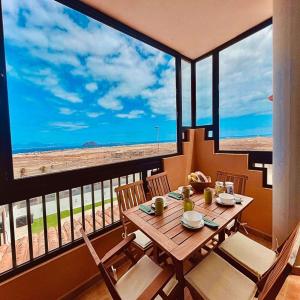 a table and chairs on a balcony with a view of the beach at Paradise Apartment in Corralejo