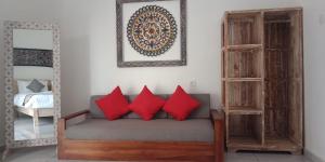 a room with a couch with red pillows and a mirror at Kapri Balinese House in Ubud