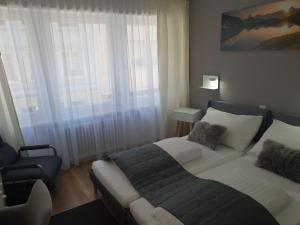 ein Schlafzimmer mit einem Bett und einem Stuhl neben einem Fenster in der Unterkunft Hotel Elite in St. Gallen
