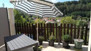 un patio con sombrilla, macetas y banco en Chambre meublée avec vue panoramique à Périgueux, en Notre-Dame-de-Sanilhac