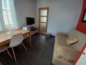 a living room with a couch and a table and a television at Les Palerées, petite maison au coeur de la Sologne des Etangs in Saint-Viâtre