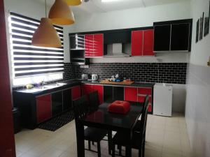 a kitchen with red cabinets and a table with chairs at LEBOK HOMESTAY AIRPORT KUANTAN in Kuantan