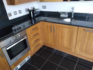 a kitchen with wooden cabinets and a sink and a stove at Room in Luxurious Penthouse Apartment in London