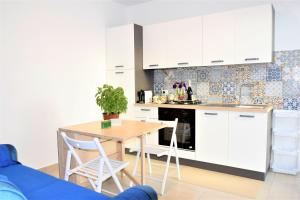 a kitchen with white cabinets and a wooden table at Pozzo Antico Apartments in San Vito lo Capo