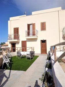 a white house with a patio and grass at Pozzo Antico Apartments in San Vito lo Capo