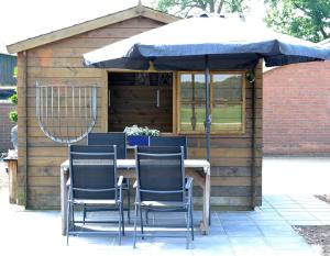 a table with chairs and an umbrella in a shed at Vakantiewoning 't Haller Vorden in Vorden