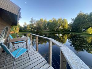 a wooden deck with a table and chairs on the water at Hôtel Restaurant Le Relais de l'Estuaire in Étauliers