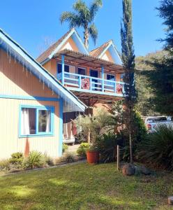 a house with a balcony and a palm tree at Residencial Saldanha in Gramado