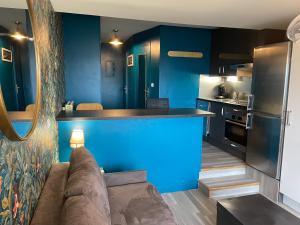 a living room with a couch and a blue kitchen at Deauville marina - Escapade vue mer in Deauville