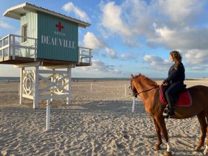 ドーヴィルにあるDeauville marina - Escapade vue merの浜辺の馬に乗る女