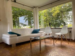 a living room with a white couch and two white chairs at Kapiteinshuis Breskens in Breskens