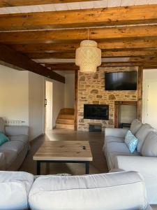 a living room with white couches and a fireplace at EL PAJAR DE LEONOR in Horcajuelo de la Sierra