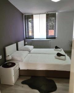 Un dormitorio con una gran cama blanca y una ventana en Apartman Bloom, en Osijek