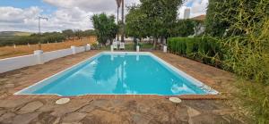 uma grande piscina azul em frente a uma casa em La Fuensanta em Hornachuelos