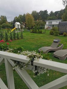 a garden with two chairs and flowers on a fence at Sapņi in Kolka