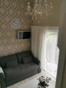 a living room with a couch and a clock on the wall at Sapņi in Kolka