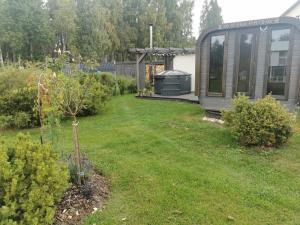 a garden with a small tree and a greenhouse at Sapņi in Kolka
