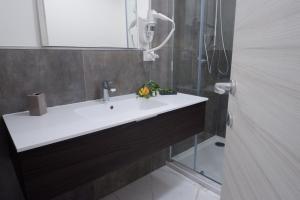 La salle de bains est pourvue d'un lavabo blanc et d'une douche. dans l'établissement Natural House, à Buonabitacolo