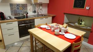 una pequeña cocina con una mesa de madera y paredes rojas en Domus Solarii Holiday Home, en Bérgamo