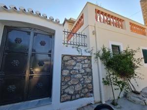 a house with black doors and a stone wall at La belle Hélène in Spetses