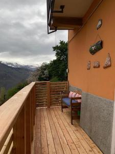 una terraza de madera con una silla y vistas a las montañas en Appartamento immerso nel cuore del parco dell Adamello, en Cimbergo