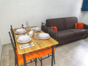 a wooden table with plates and glasses and a couch at Modern Apartment in Central Bugibba in St. Paul's Bay