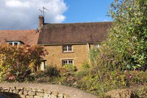 stary ceglany dom z kamiennym murem przed nim w obiekcie Cotswolds Cottage Ilmington with Wood Burning Stove & BBQ - pet friendly w mieście Chipping Campden