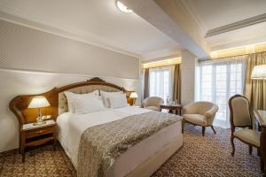 um quarto de hotel com uma cama, cadeiras e janelas em Residence City Garden - Certificate of Excellence 3rd place in Top 10 BEST Five-Stars City Hotels for 2023 awarded by HTIF em Plovdiv
