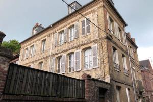 un viejo edificio de ladrillo con una valla delante en Sous les toits en Dieppe