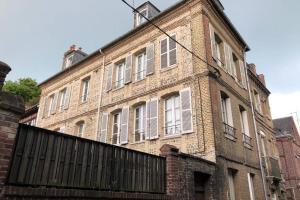 an old brick building with a fence in front of it at Sous les toits in Dieppe
