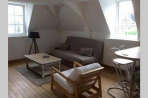 a living room with a couch and a table at Sous les toits in Dieppe +2 photos