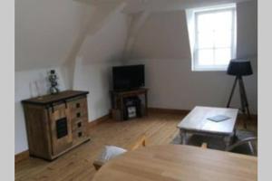 a living room with a table and a television at Sous les toits in Dieppe