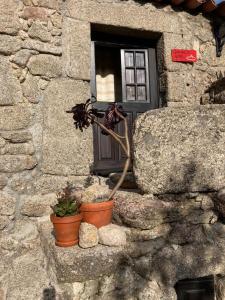 una ventana de un edificio de piedra con dos macetas de flores en Casa das 5 Cruzes dentro da muralha, en Sortelha